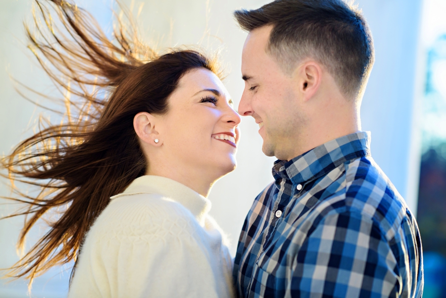 The winds blowing through a woman's hair as her fiance kisses her in their DC engagement session.